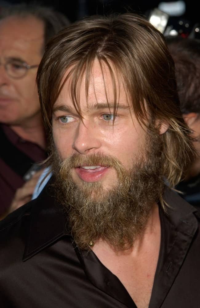 A long-haired Brad Pitt in a black shirt. He has a thick beard as well.