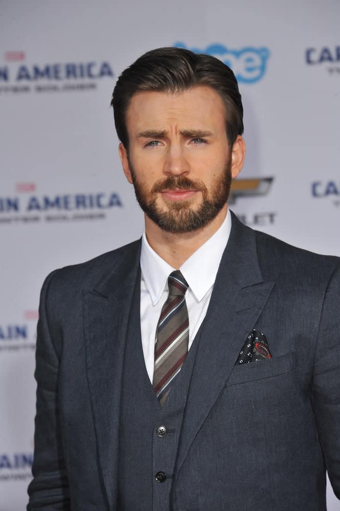 On March 13, 2014, Chris Evans wore a classy three-piece suit with his dark side-parted slick hairstyle at the world premiere of his movie "Captain America: The Winter Soldier" at the El Capitan Theatre, Hollywood.