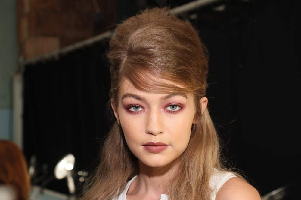 Gigi Hadid was at the backstage before the Anna Sui Spring 2017 Fashion Show on September 14, 2016 in New York City. Her hair was styled to a unique half up hairstyle with a beehive finish.