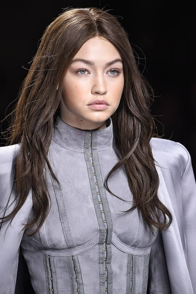 Gigi Hadid was dressed in a detailed gray dress to go with her loose and tousled dark hairstyle at the runway during the Balmain show on March 3, 2016 in Paris, France.