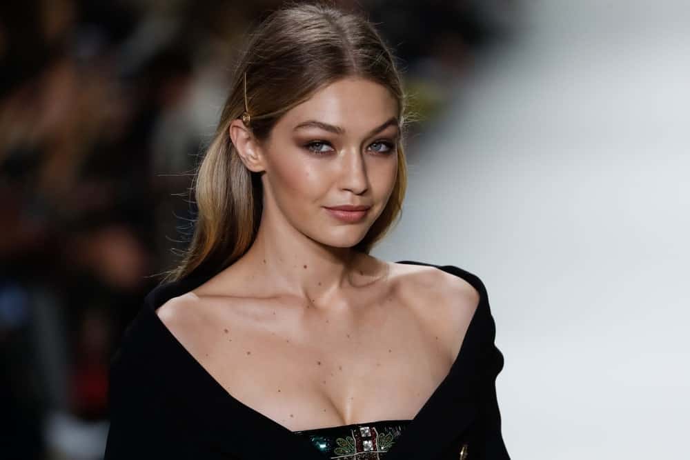 Gigi Hadid flashed her lovely smile with her pinned half up hairstyle when she walked the runway at the Versace show during Milan Fashion Week Spring/Summer 2018 on September 22, 2017 in Milan, Italy.