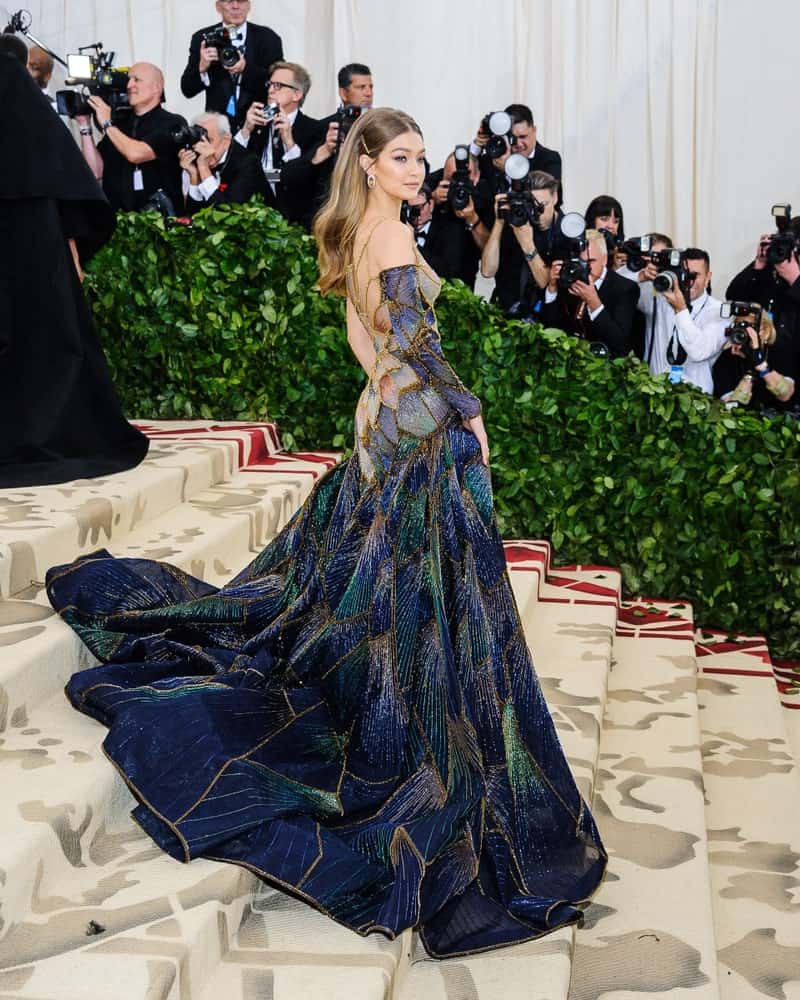 Gigi Hadid attended the 2018 Metropolitan Museum of Art Costume Institute Gala with the theme, Heavenly Bodies: Fashion and the Catholic Imagination. She came in a beautiful and colorful long gown with her ombre hair in a half up pinned hairstyle.