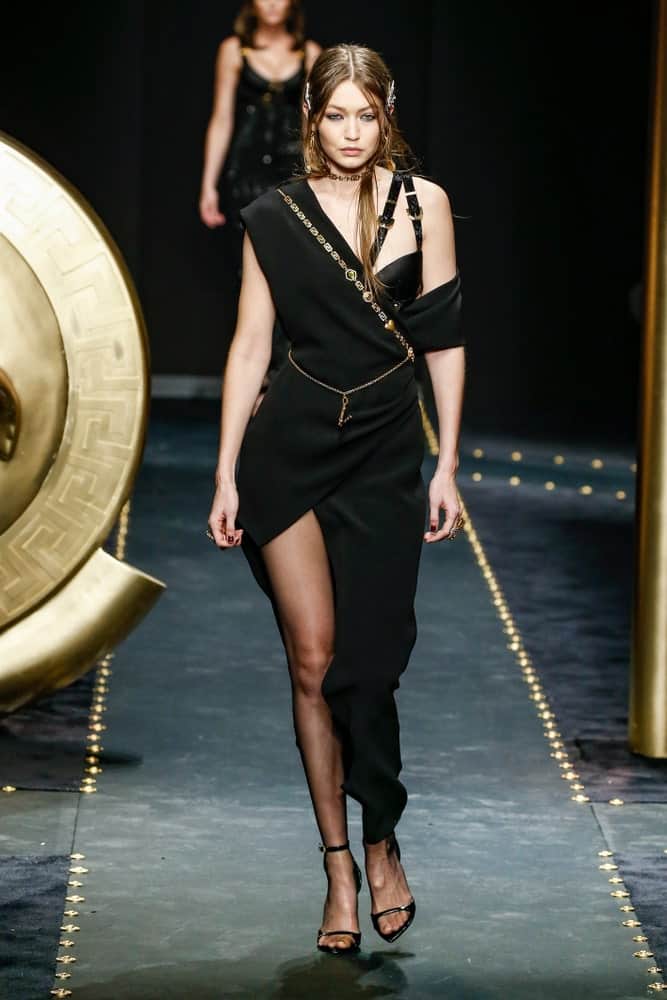 Gigi Hadid walked the runway at the Versace show at Milan Fashion Week Autumn/Winter 2019/20 on February 22, 2019 in Milan, Italy. She was dressed in a goddess-like black dress and her hair was pinned into a half-up hairstyle.