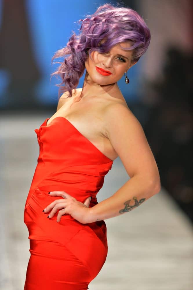 Kelly Osbourne looking stunning with the purple hair and the red dress. She's posing on the runway at The Heart Truth's Red Dress Collection on the 6th of February 2013.