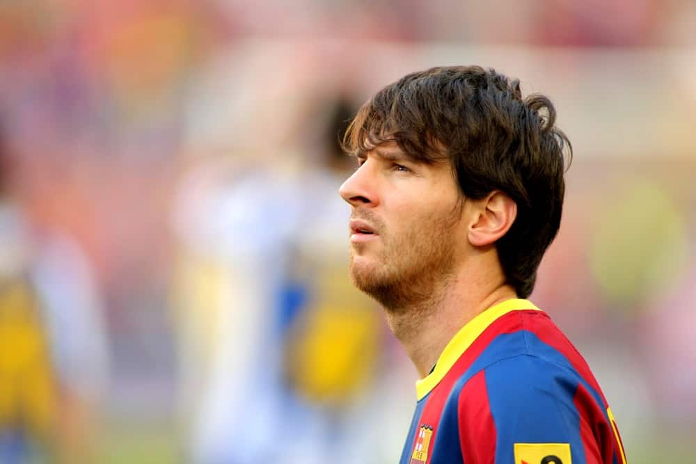Lionel Messi of FC Barcelona looked at the scoreboard during the match between FC Barcelona and RCD Espanyol at the Nou Camp Stadium on May 8, 2011, in Barcelona, Spain. He paired his red and blue uniform with a long fringe hairstyle.