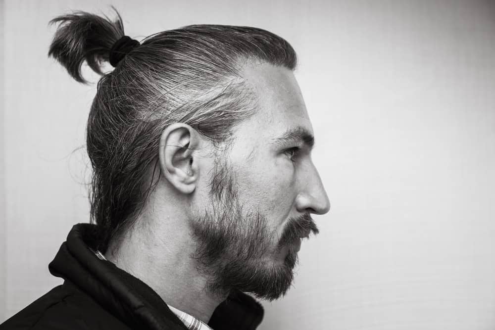 Side profile of a man with ponytail and beard.