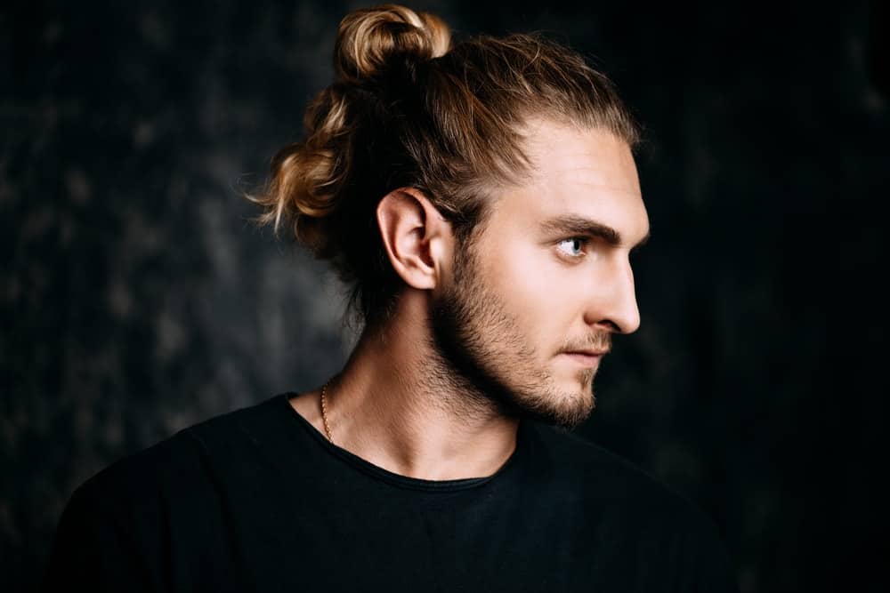 Side profile of a blonde man sporting a ponytail hairstyle.