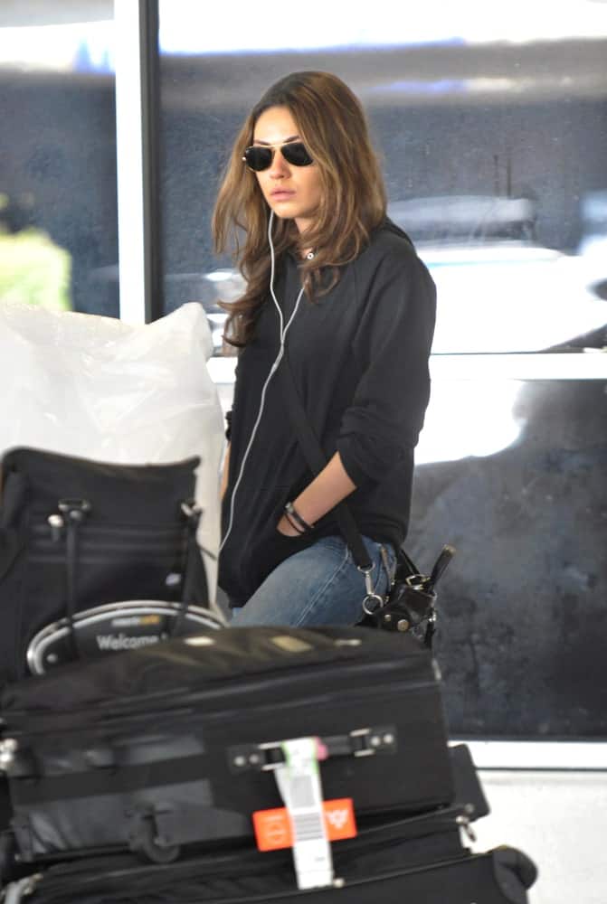 The actress Mila Kunis was seen at LAX last October 23, 2010 in Los Angeles, California. She opted for a casual black hoodie jacket paired with a reddish brown dyed loose tousled hair.