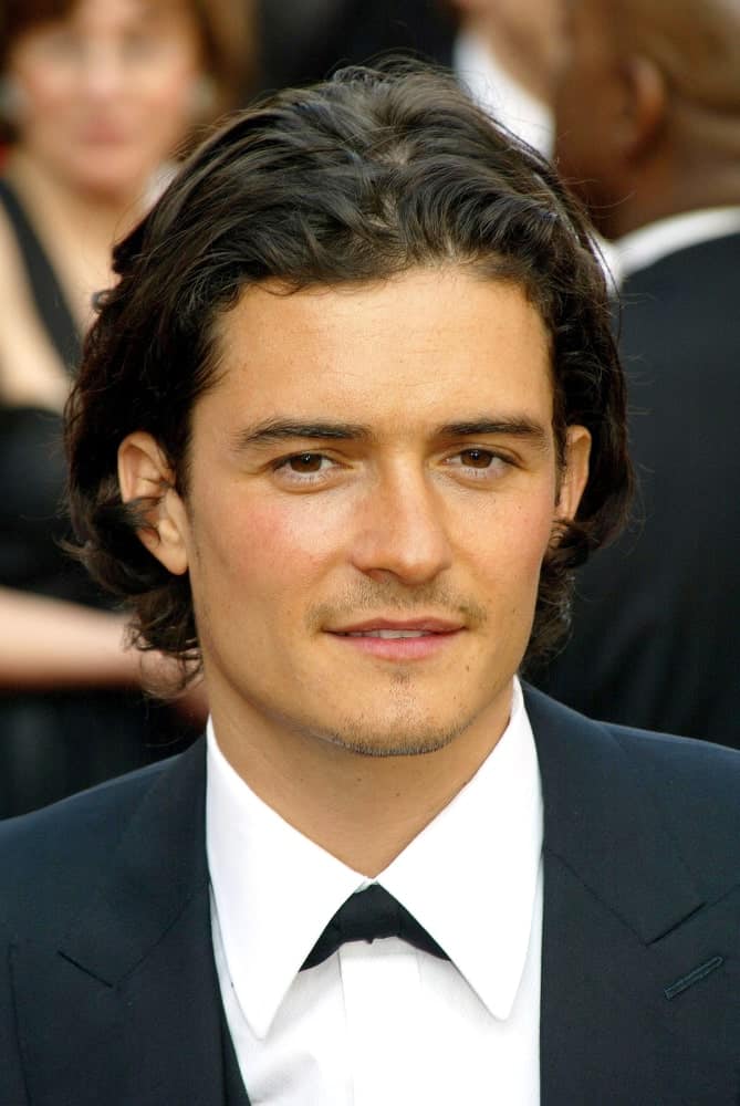 Orlando Bloom's medium-length hair was brushed-back and parted in the middle with curls at the tips on February 27, 2005 at the 77th Annual Academy Awards Oscar Ceremony in Los Angeles.