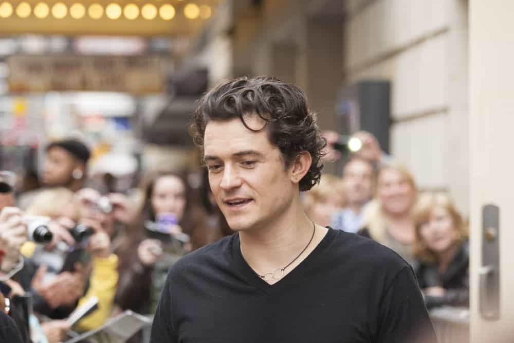 Orlando Bloom gave autographs prior to "Romeo and Juliet" performance at Richard Rogers Theater on October 9, 2013 in New York. He wore a casual black shirt with his gorgeous dark curly hair.