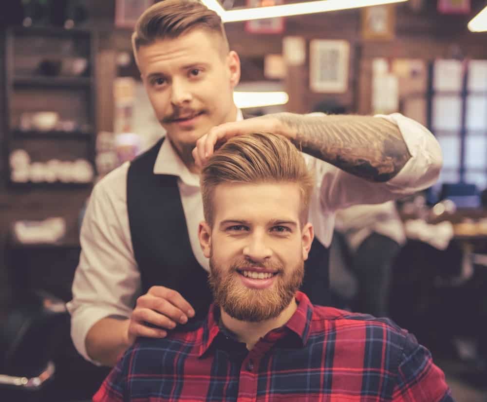 A bearded man having his done by a barber.