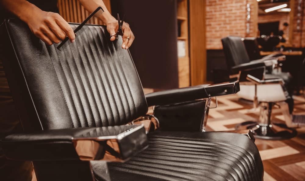 A barber's chair with cushioned black leather seat.