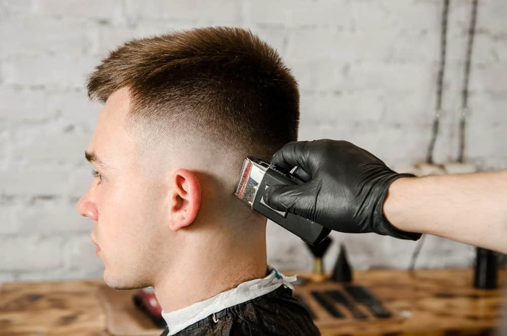 A man having a fade haircut with the use of a hair clipper.
