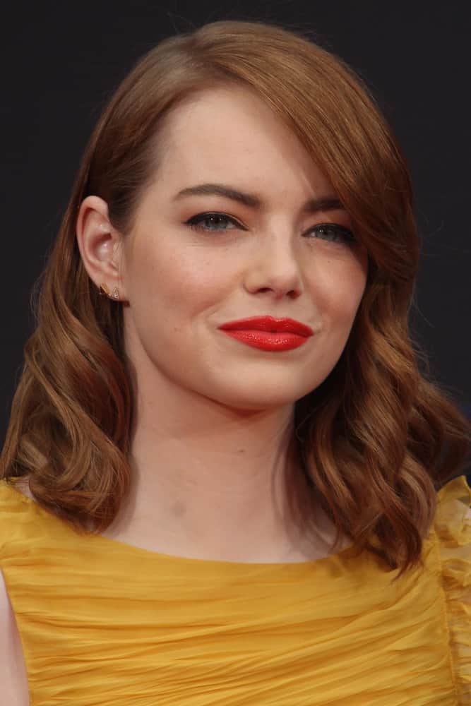 Emma Stone, along with Ryan Gosling, was honored with a Hand and Foot Print Ceremony at TCL Chinese Theater on December 7, 2016 in Los Angeles, CA. She was lovely in her yellow cocktail dress that she paired with long and wavy red hair