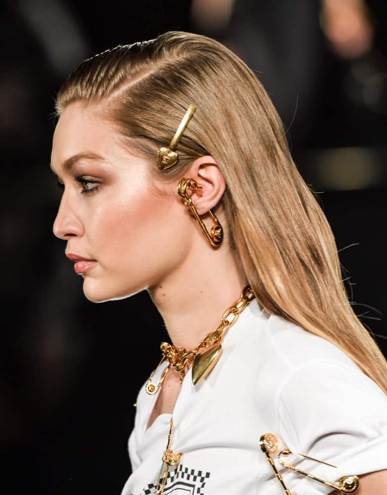 On December 2, 2018, Gigi Hadid walked the runway at the Versace Pre-Fall 2019 Collection at The American Stock Exchange. Her hair was styled with pins into a slick half-up hairstyle with subtle highlights.