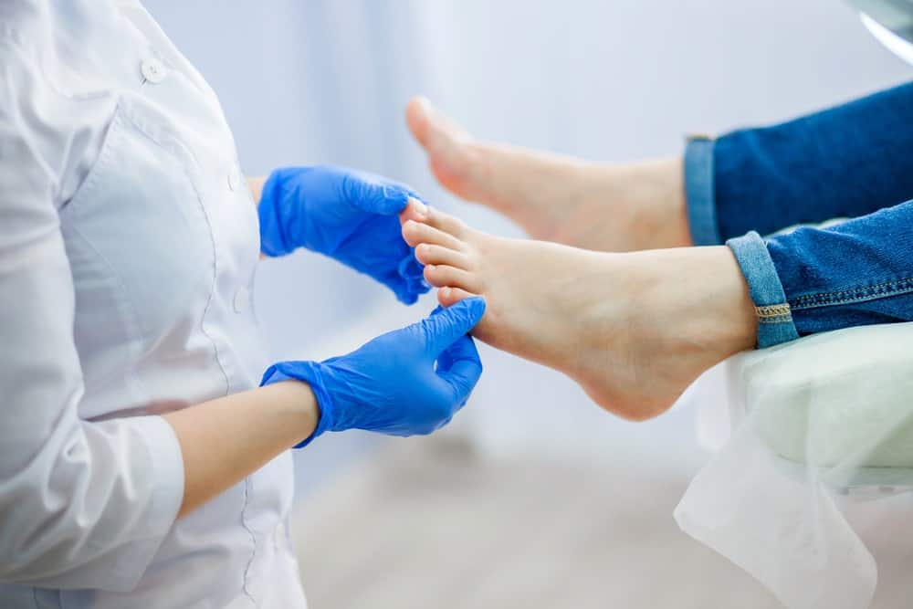 A healthcare professional examining a foot of a patient.