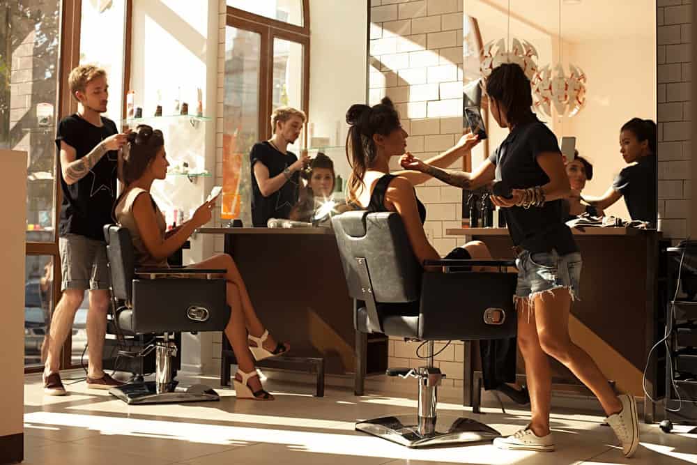 A couple of women having their hair done in a bright and airy salon.