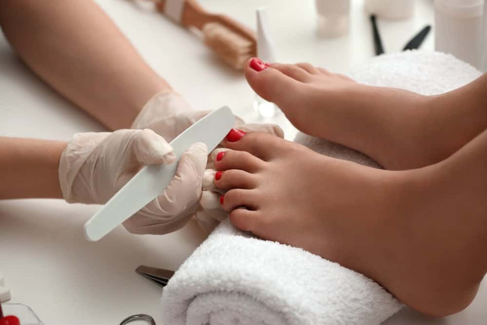A woman with red nails having a pedicure.