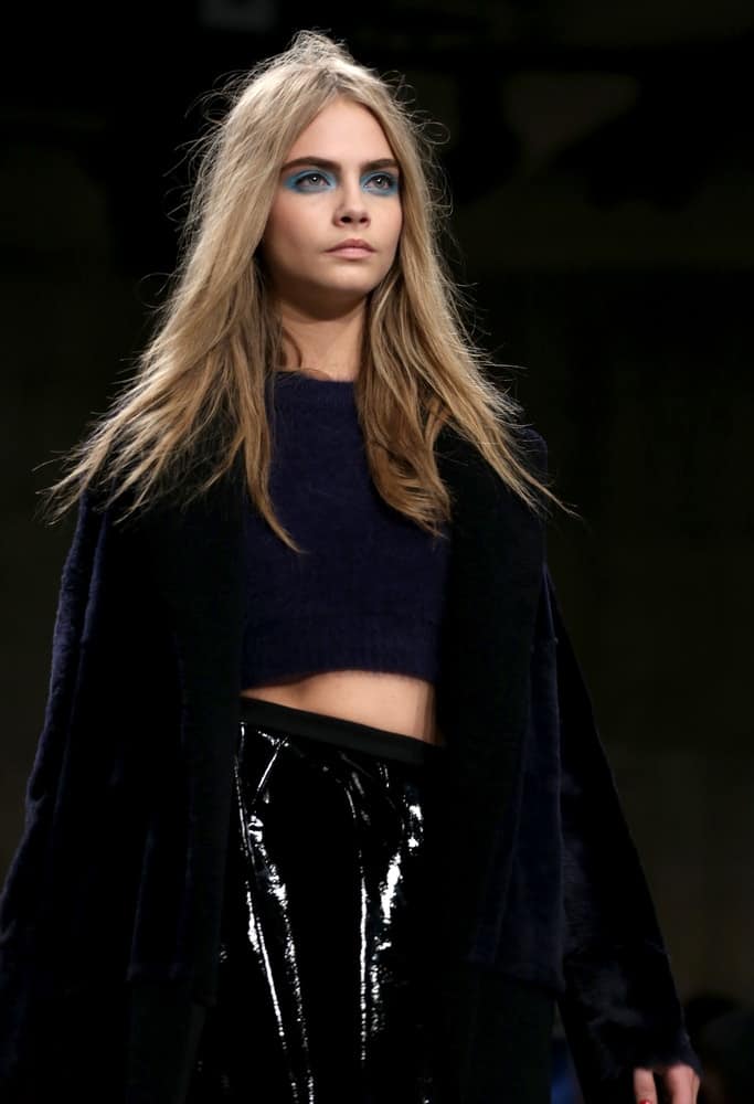 Cara Delevingne’s center-parted loose and tousled sandy blond hairstyle were complemented by bold blue eye make-up at the Unique show as part of London Fashion Week AW13 in Tate Modern, London on February 17, 2013.