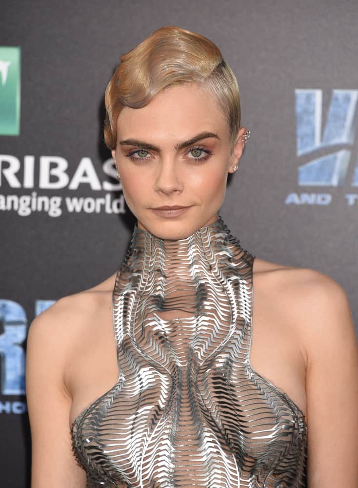 Cara Delevingne attended the “Valerian And The City Of A Thousand Planets” World Premiere on July 17, 2017, in Hollywood, CA. She was quite fashionable in the metallic futuristic dress that she paired with a slick side-parted bun hairstyle with a sandy blond tone.