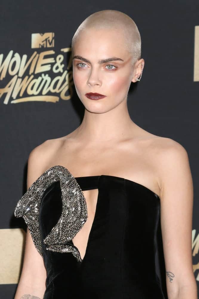 Cara Delevingne went with an edgy platinum blond buzz cut to go with her bold make-up and black dress at the MTV Movie and Television Awards on the Shrine Auditorium on May 7, 2017, in Los Angeles, CA.