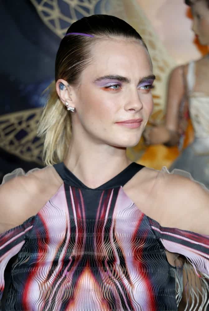 Cara Delevingne wore an elegant colorful dress to pair with her colorful make-up and multi-colored, slick ponytail hairstyle at the Los Angeles premiere of Amazon’s ‘Carnival Row’ held at the TCL Chinese Theatre in Hollywood, USA on August 21, 2019.