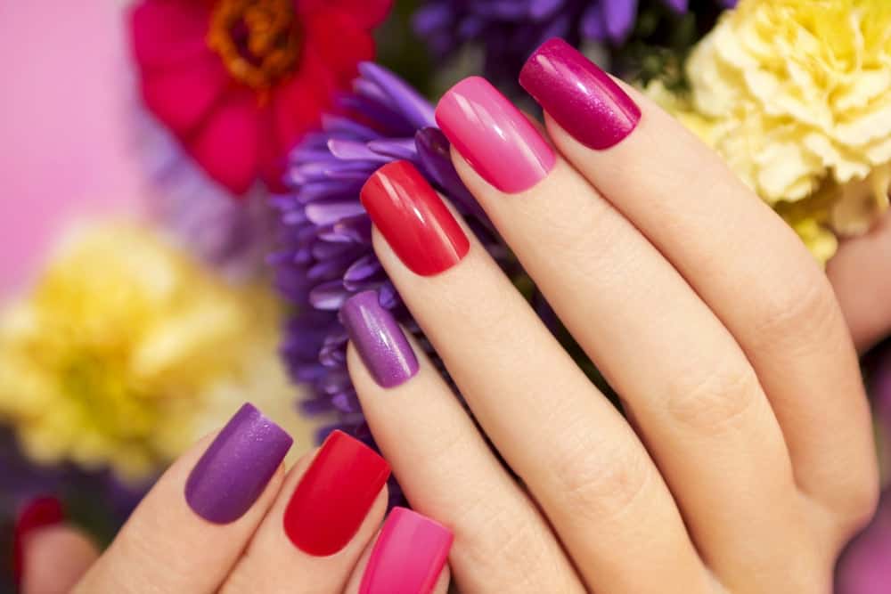 A close-up of a woman's hands with different-colored nails.