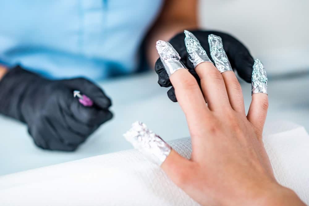 A woman having her nails done in a salon with soak off gel.