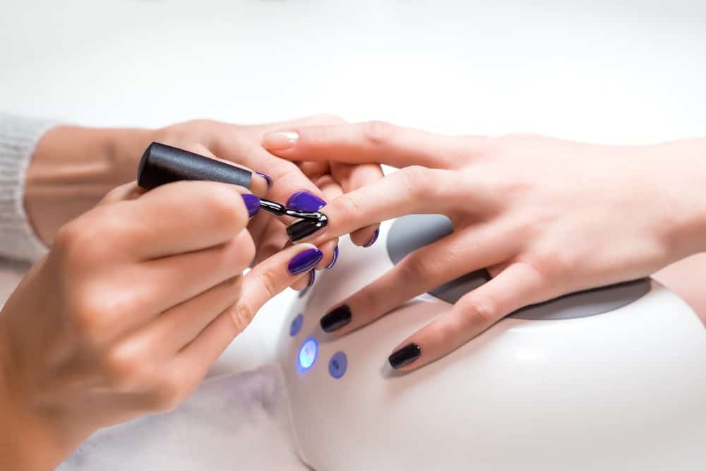 A manicurist applying nail gel polish on a client.