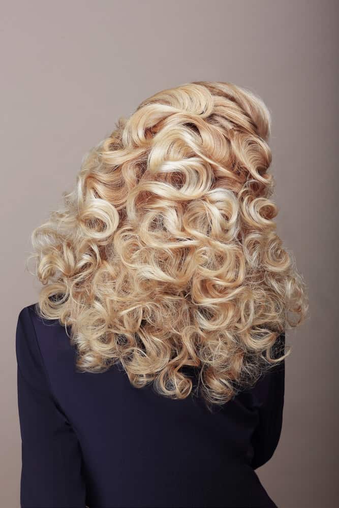 A woman with blond loose curls as seen from behind.