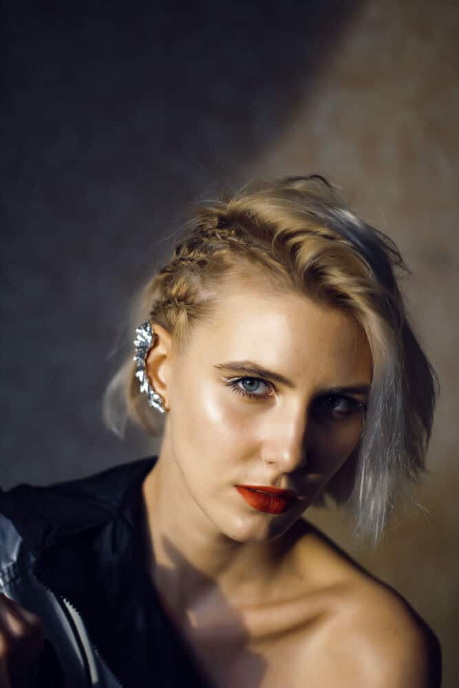A woman with side-swept short blonde hair and braided three spikelets.