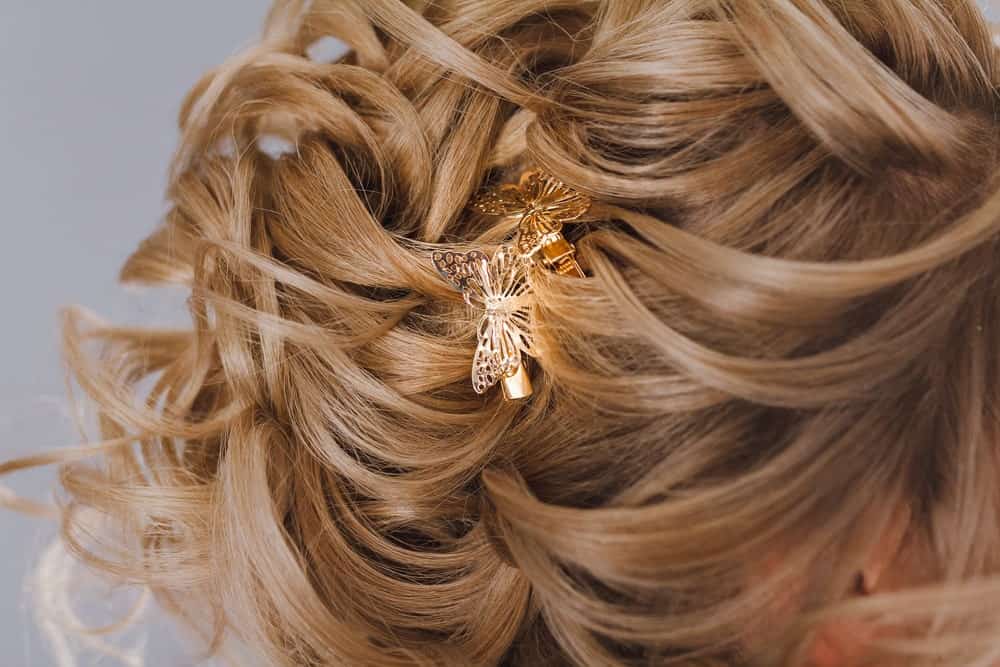 Woman's brown curly hair pinned with butterfly clips.
