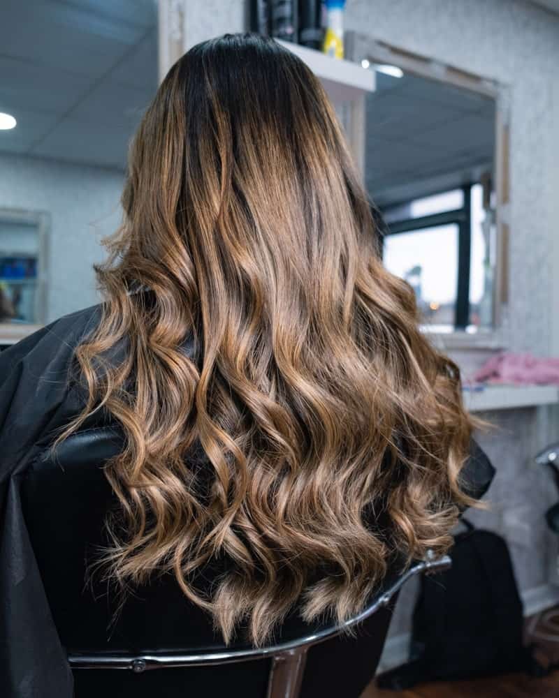 A woman with a long and wavy balayage hairstyle.