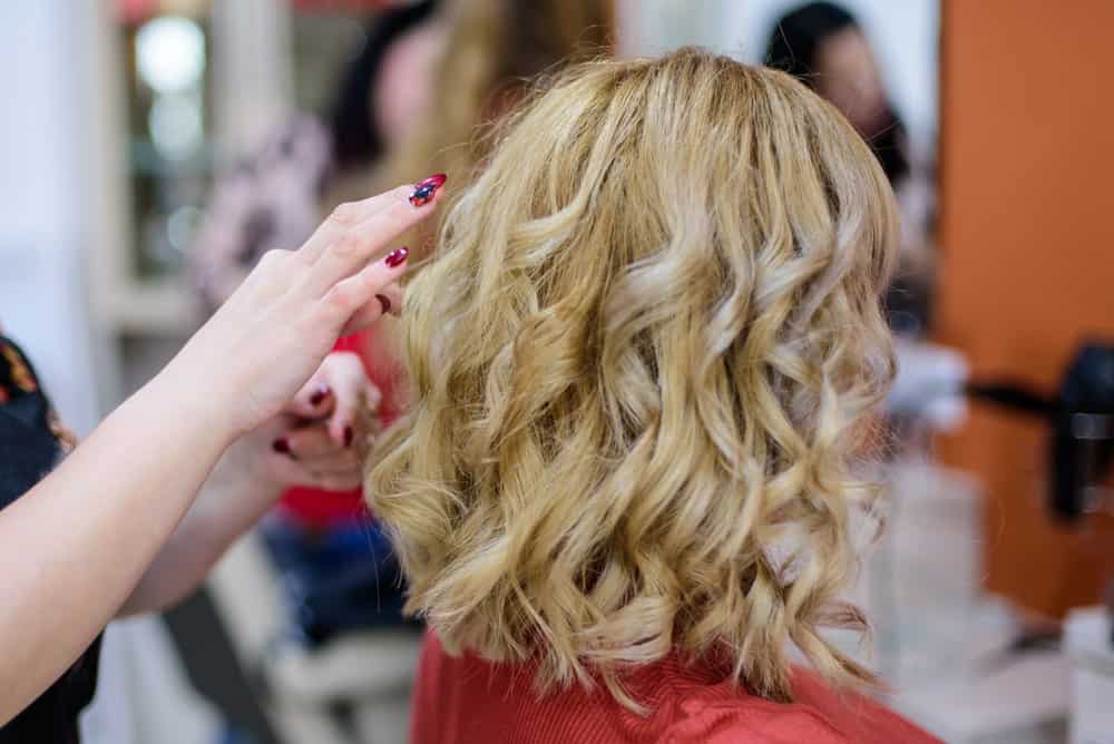 Female hairdresser styling the woman's blonde hair.
