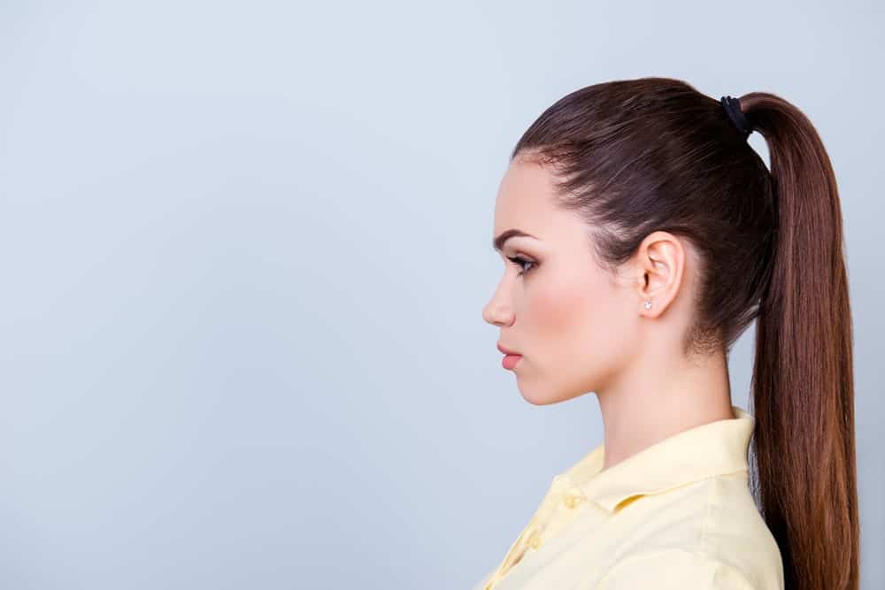 Side profile of a woman in yellow polo shirt with a high ponytail.