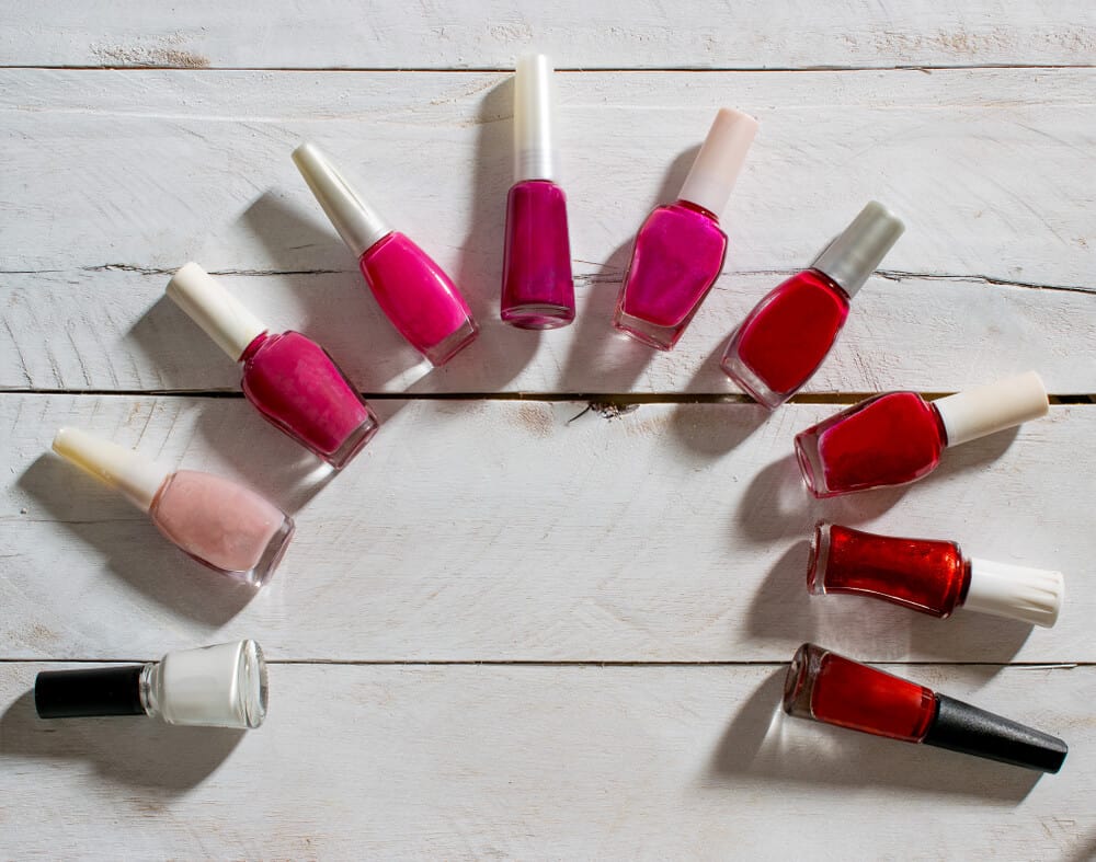 Nail polish bottles on a semi-circle against a whitewashed pallet background.