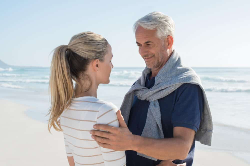 An elderly couple looking at each other at a beachside.