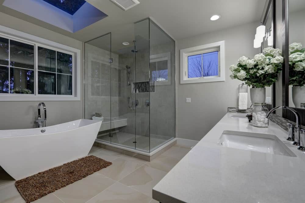 Gray bathroom with a walk-in shower, a freestanding tub, and a dual sink vanity.