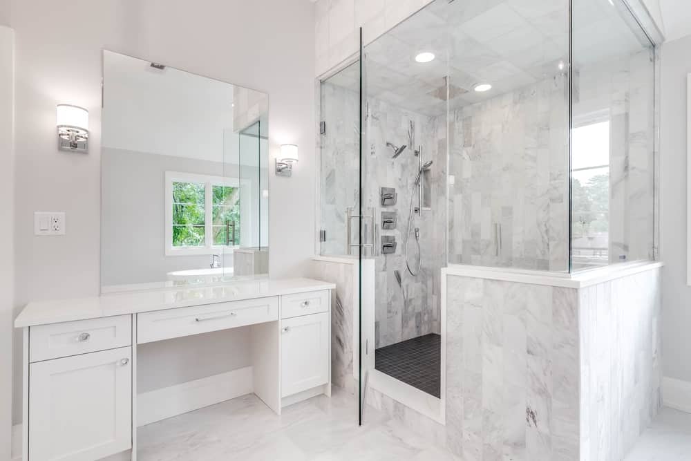 Bathroom with a walk-in shower and a white vanity paired with a frameless mirror.