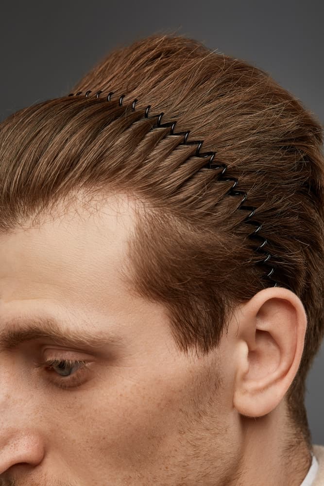 A close look at a man wearing a thin black wavy headband.