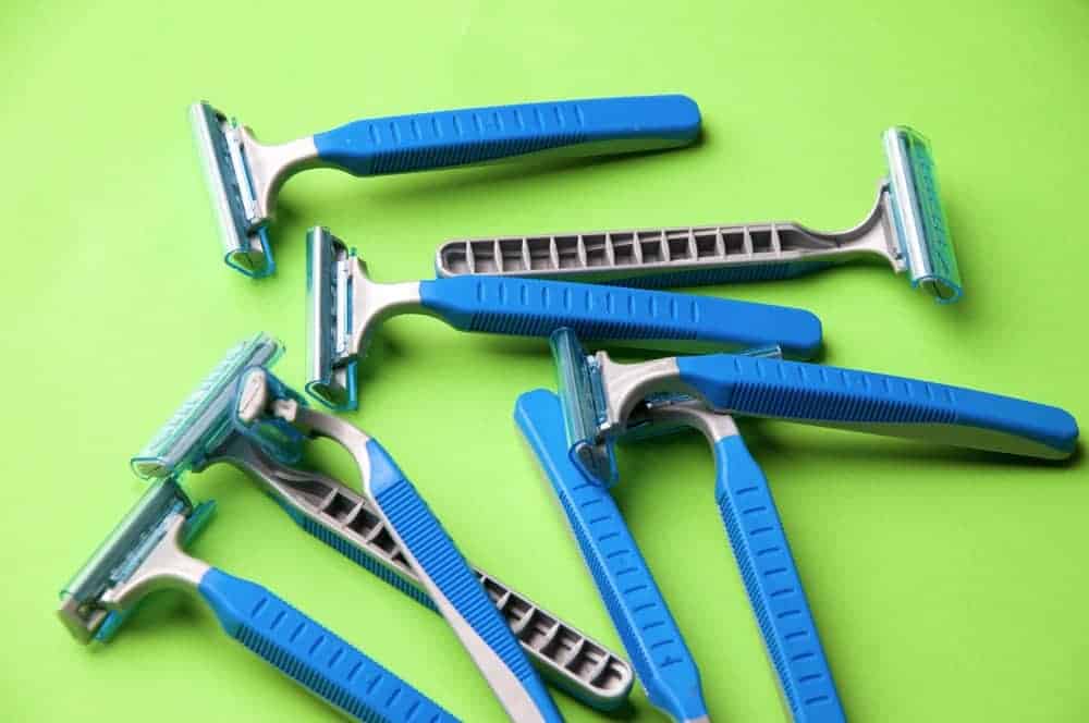 Blue disposable razors against green background.