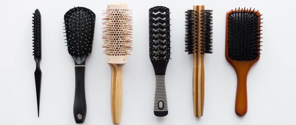 A row of hair brushes on a white surface.