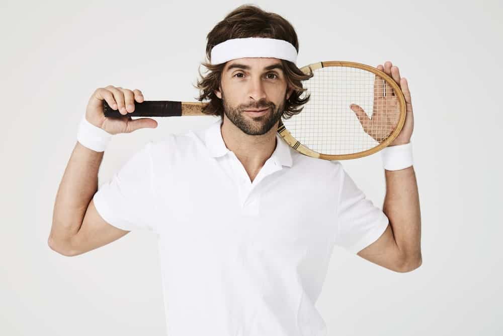 A long-haired man wearing a white tennis headband.