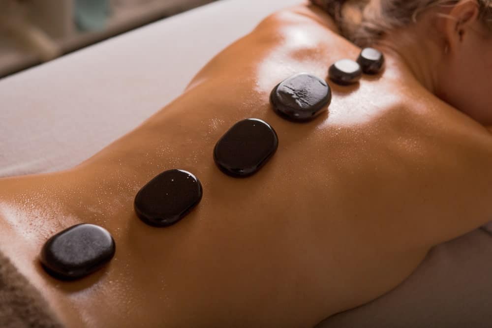 A woman on a massage table having a hot stone massage.
