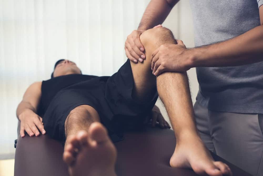 A sports therapist massaging the knee of an athlete.