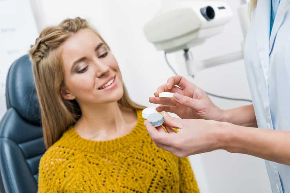 Optician putting contact lens in her patient's eyes.