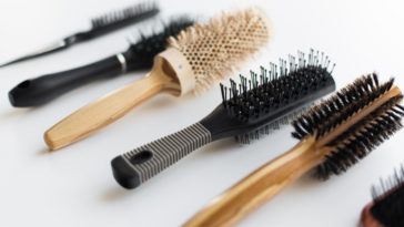A variety of different brushes and combs on a white surface.