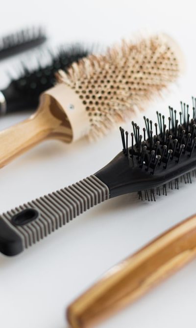 A variety of different brushes and combs on a white surface.
