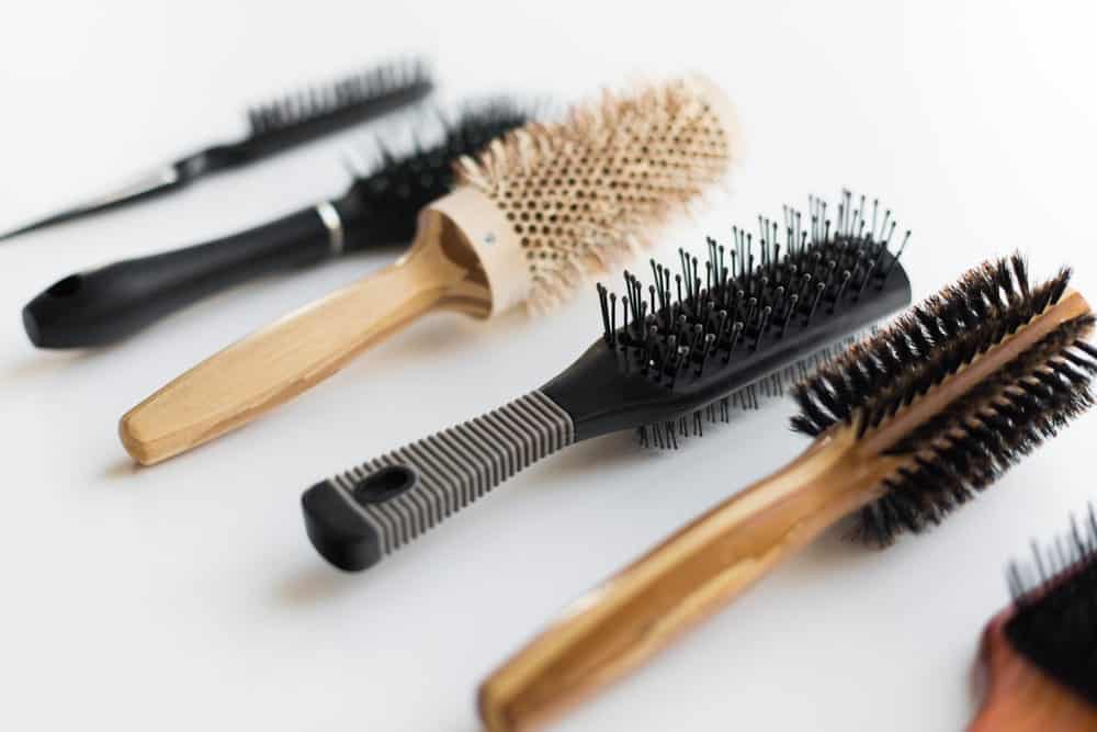 A variety of different brushes and combs on a white surface.