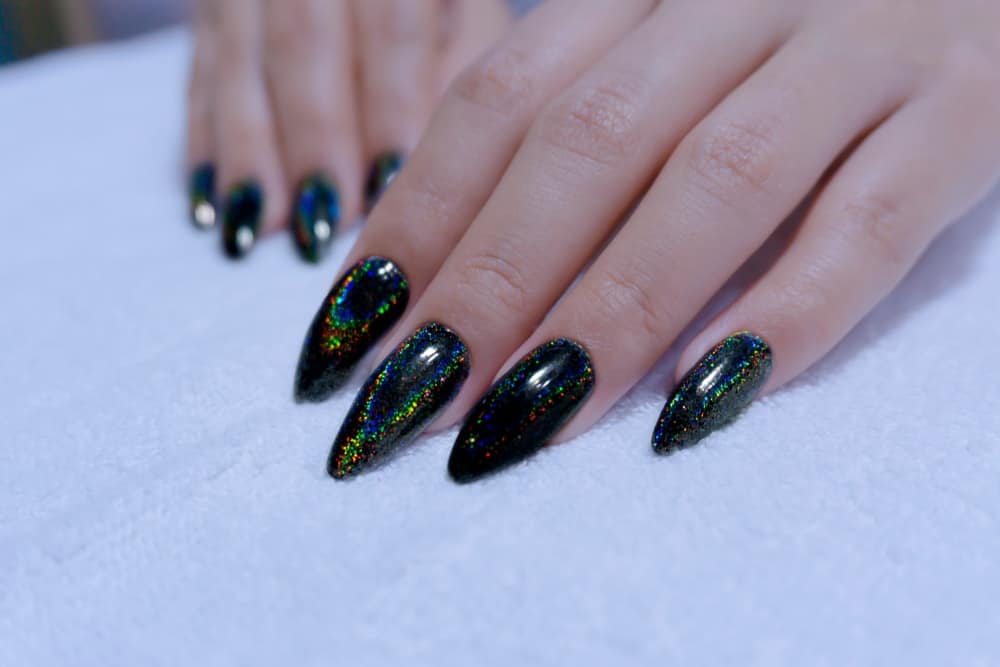 Closeup of fingernails painted in black gel hologram nail polish.